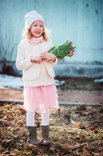 Feliz niña sonriente con tulipanes ramo en el paseo en el día de primavera — Foto de Stock