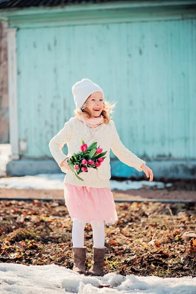 快乐儿童小女孩微笑着与郁金香花束上的走在春天的一天 — 图库照片