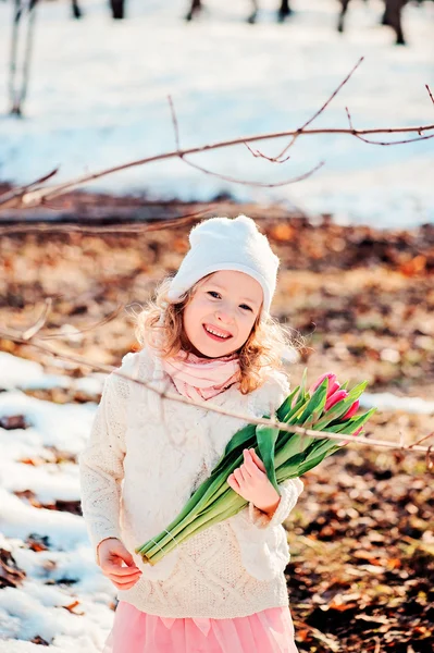 Spring portrait of happy smiling child girl with tulips bouquet on the walk in sunny day — Stock Photo, Image