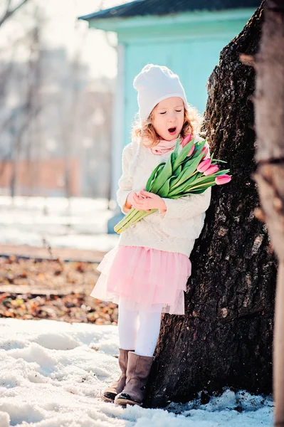 Linda niña con tulipanes ramo para el día de la mujer en el paseo en primavera — Foto de Stock