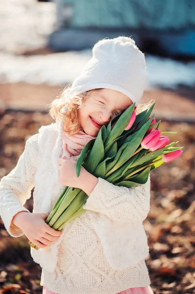 可爱的孩子小女孩微笑着与妇女节上走在春天的郁金香花束 — 图库照片
