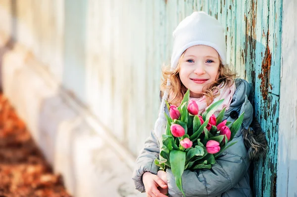 Spring portrait of happy child girl with tulips on the walk — Stock Photo, Image