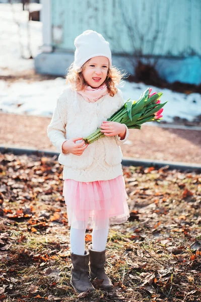 Child girl with tulips bouquet on the walk in early spring day — Stock Photo, Image