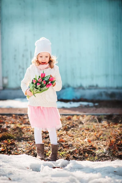 Child girl with tulips bouquet on the walk in early spring day — Stock Photo, Image