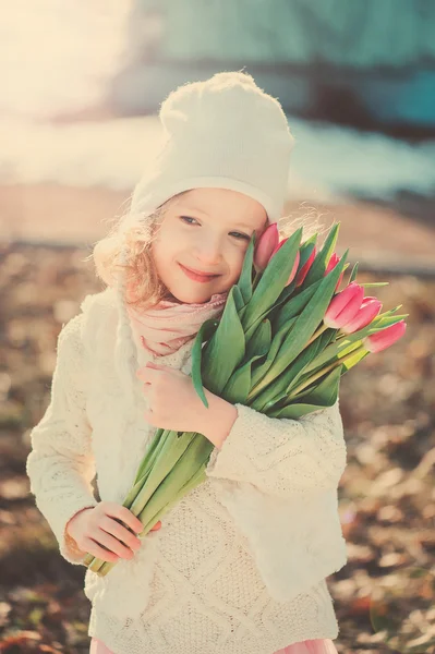 Spring vintage tones portrait of happy child girl with tulips bouquet for woman's day — Stock Photo, Image