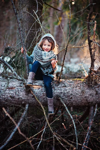 Šťastné dítě dívka na procházce v lese brzy na jaře seděl na staré borovice — Stock fotografie