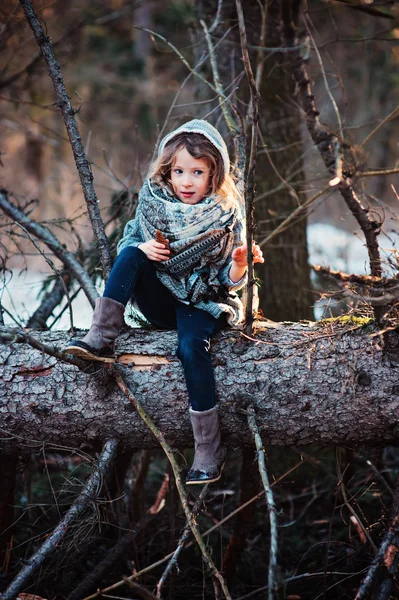 Oturma ve erken Bahar ormandaki yaşlı çam ağacı üzerinde oyun kız çocuk — Stok fotoğraf
