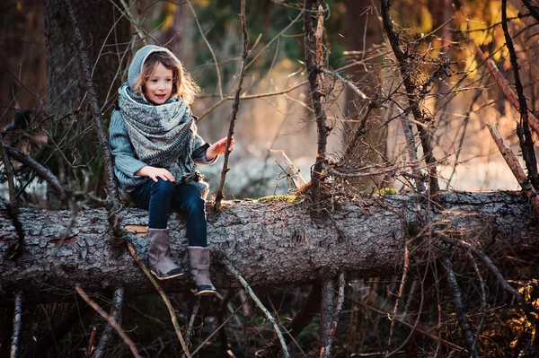 Šťastné dítě dívka na procházce v lese brzy na jaře seděl na staré borovice — Stock fotografie