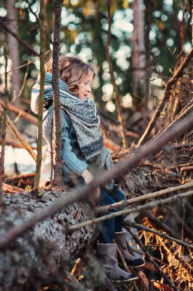 Lyckligt barn flicka sitter och spelar på gammal tall i tidig vår skog — Stockfoto