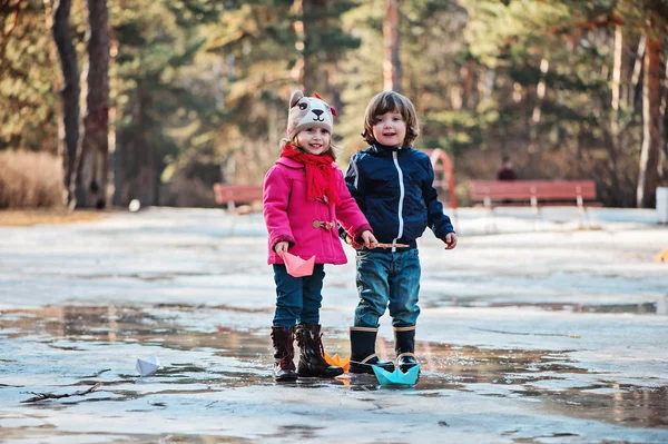 Bambino ragazzo e ragazza divertirsi e giocare barche di carta in pozzanghera primavera — Foto Stock