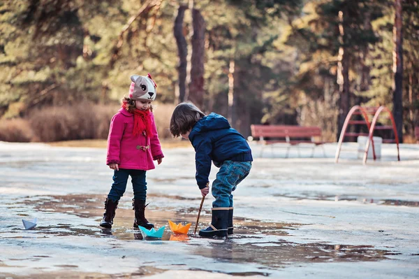 Peuter jongen en meisje met plezier en spelen papier boten in voorjaar Plas — Stockfoto