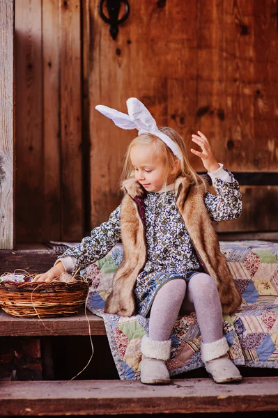 Happy child girl wearing bunny ears for easter at wooden country house — Stock Photo, Image