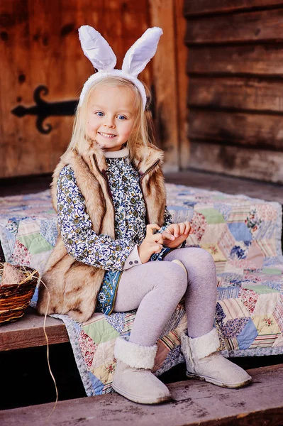 Lyckligt barnflickan bär bunny öron till påsk på trä country house — Stockfoto