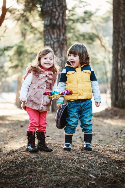 Los amigos de los niños pequeños son felices jugando al remolino en el bosque soleado. — Foto de Stock