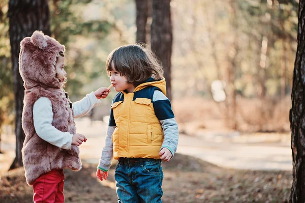 Happy toddler girl giving cookie to her friend on the walk in forest — Stock Photo, Image