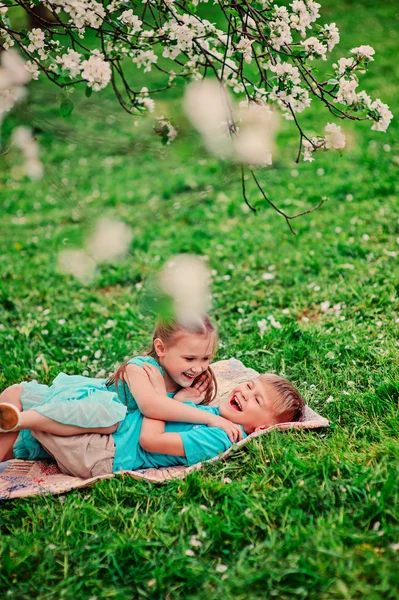 Happy brother and sister in blooming garden — Stock Photo, Image