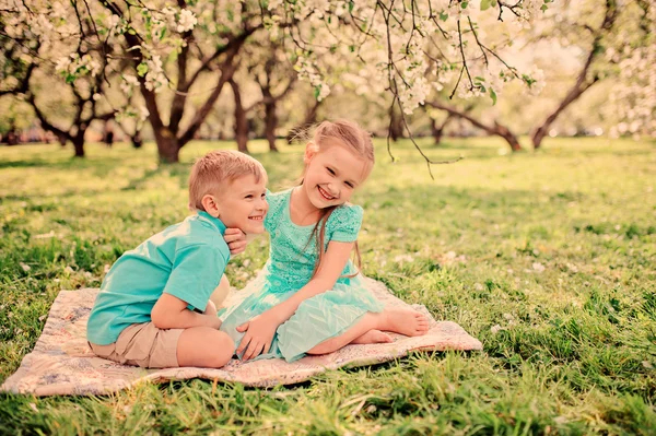 Happy brother and sister in blooming garden — Stock Photo, Image