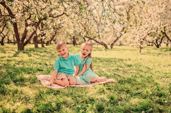 Happy brother and sister in blooming garden — Stock Photo, Image