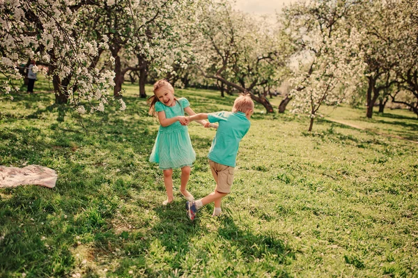 Happy brother and sister in blooming garden