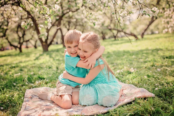 Happy brother and sister playing in spring apple blooming garden — Stock Photo, Image