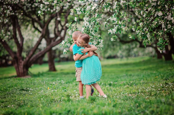 Šťastný bratr a sestra hraje v jarní apple kvetoucí zahrada — Stock fotografie