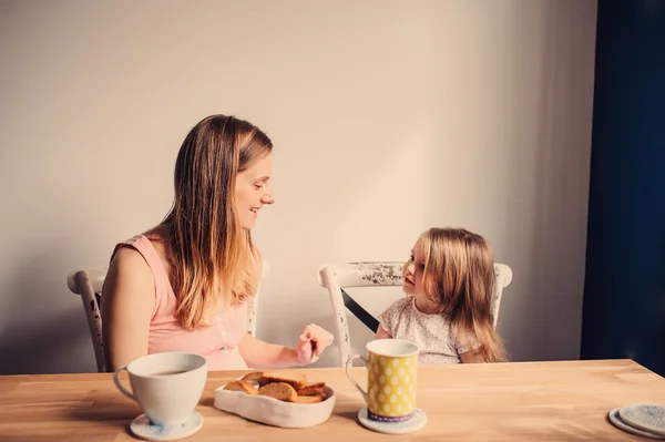 Feliz mãe amorosa e filha da criança tomando café da manhã em casa na cozinha — Fotografia de Stock