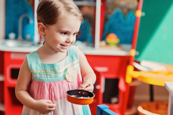 Girl playing with toy kitchen — Stock Photo, Image