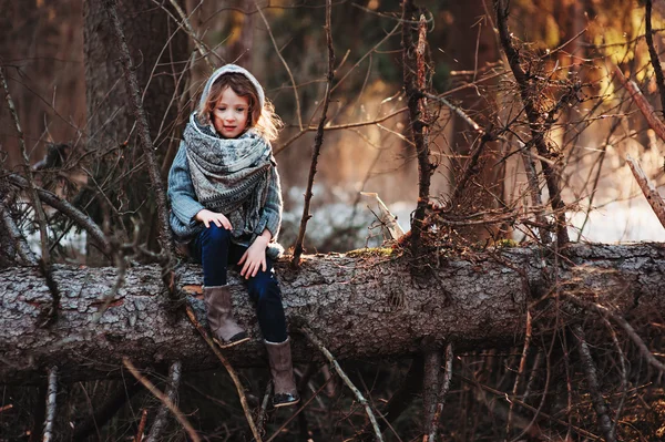Девочка сидит на сосне на уютном теплом открытом воздухе зимняя прогулка в снежном лесу — стоковое фото