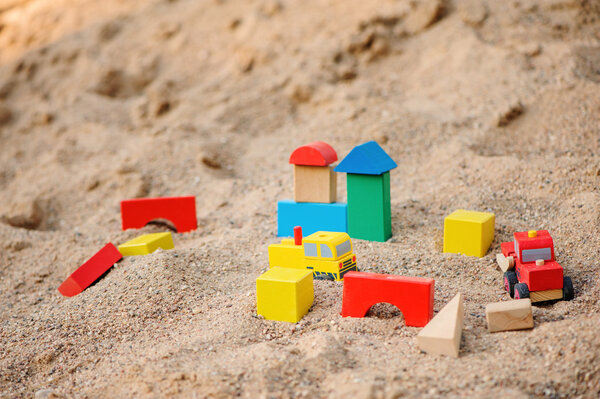 красочные деревянные кирпичи и грузовики в песочнице
