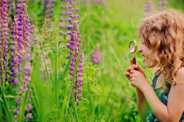 Child girl exploring nature with loupe, learning on summer vacation in forest — Stock fotografie