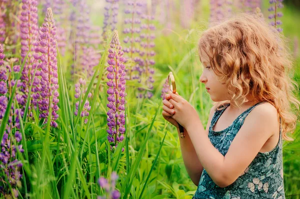 Child girl exploring nature with loupe, learning on summer vacation in forest — 图库照片