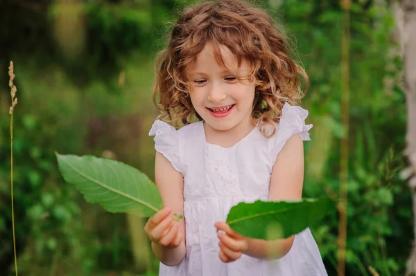 Милая девочка с зелеными листьями — стоковое фото