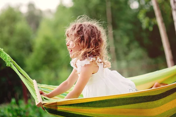 Happy child girl relaxing in hammock, cozy warm summer scene — Stock Photo, Image