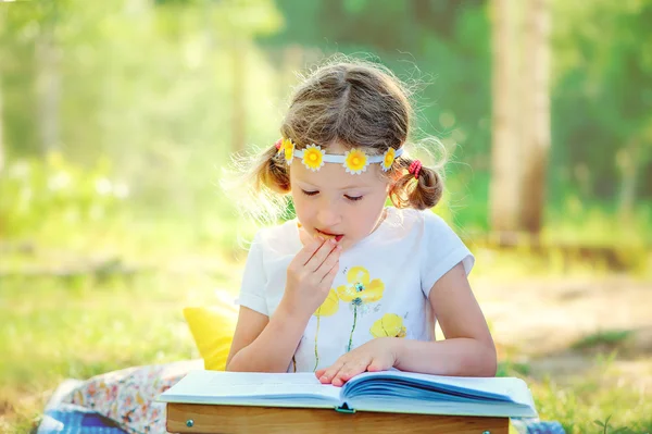 Lilla flickan läsa bok i trädgården — Stockfoto
