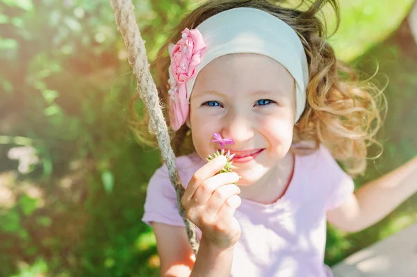 Счастливая девочка на качелях в саду — стоковое фото