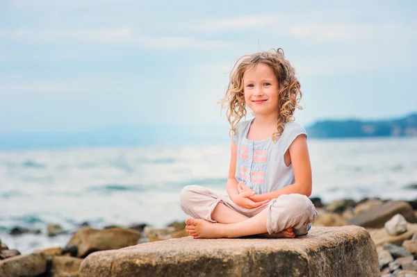 Sonriente niña relajándose en piedra grande — Foto de Stock