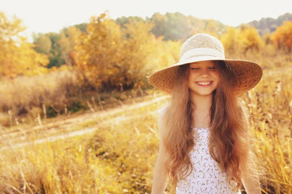 Menina criança feliz na palha se divertindo ao ar livre no verão campo ensolarado — Fotografia de Stock