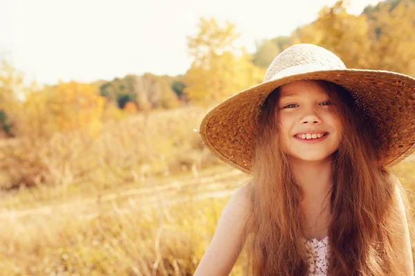 Ragazzina felice in paglia divertirsi all'aperto sul campo estivo soleggiato — Foto Stock