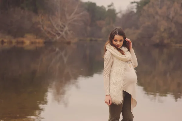 Feliz hermosa mujer embarazada en acogedor paseo al aire libre en el lado del río, suave tono cálido —  Fotos de Stock