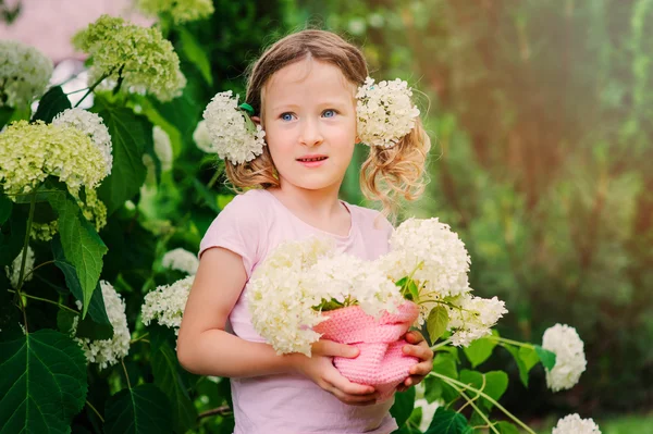 Szczęśliwe dziecko dziewczynka z bukiet hortensji gra odkryty w przytulnym ogrodzie — Zdjęcie stockowe
