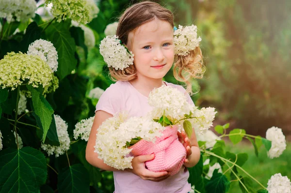 Šťastné dítě dívka s kytice hortenzie hraje venkovní v útulné letní zahrada — Stock fotografie