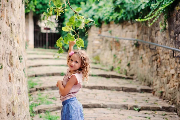 Happy kid girl on the walk in old city at stone wall, travelling on summer vacation in Slovenia — Stock Photo, Image