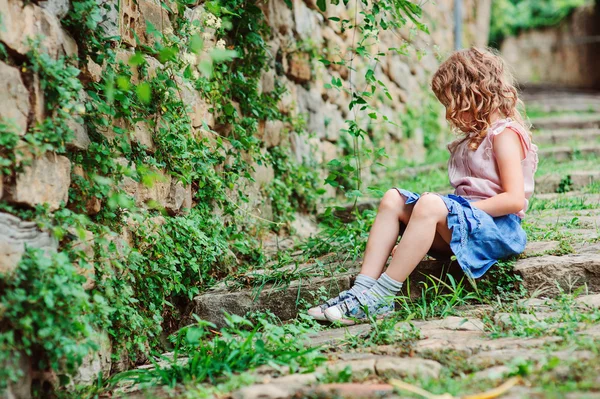 Счастливая девочка на прогулке по старому городу у каменной стены, путешествуя на летние каникулы в Словеню — стоковое фото