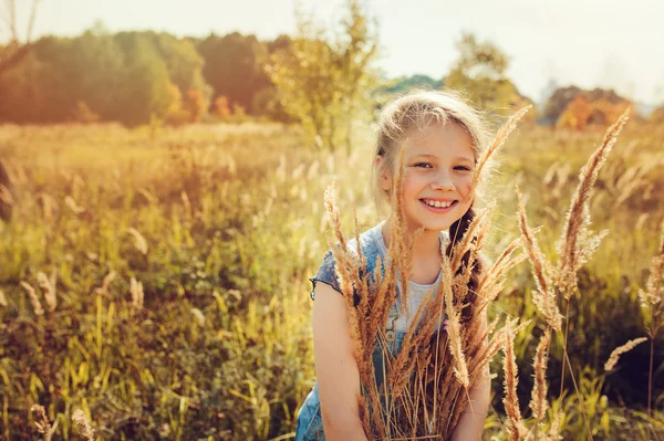 Bambino felice ragazza in jeans nel complesso giocando sul campo di sole, stile di vita all'aperto estivo, umore accogliente — Foto Stock