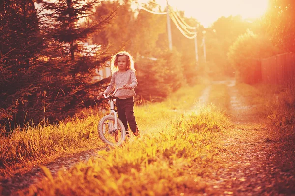 Катание на велосипеде для девочек на летней сельской дороге, сезонные развлечения на открытом воздухе — стоковое фото