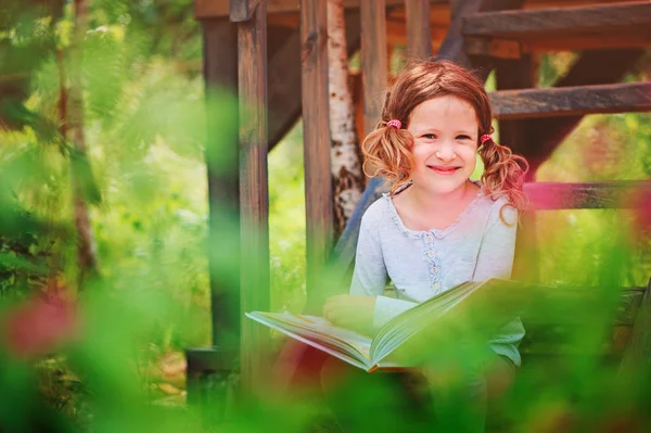 Menina feliz ler livro ao ar livre, aprendendo nas férias de verão — Fotografia de Stock