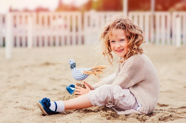 Niña feliz jugando con el pájaro de juguete en la playa en las vacaciones de verano — Foto de Stock