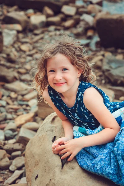 Niña feliz relajándose en la playa, envuelta en una acogedora manta de edredón — Foto de Stock