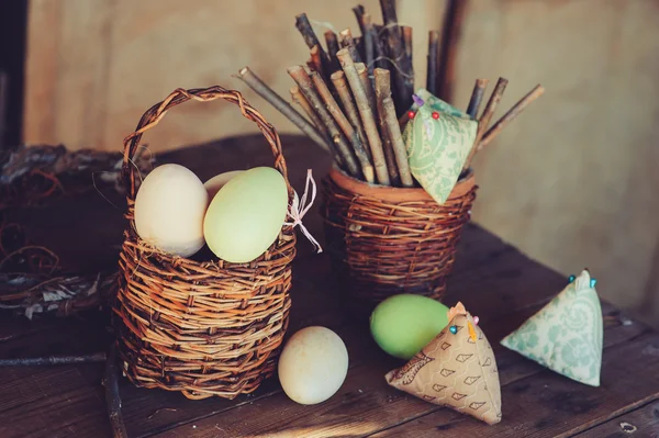 Великодні яйця та прикраси на дерев'яному столі в затишному заміському будинку, вінтажний тонований — стокове фото
