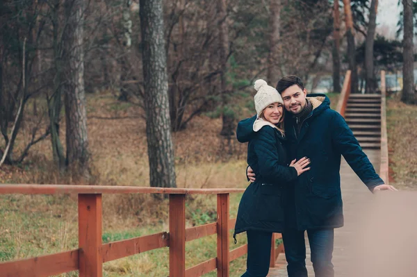 Casal feliz em chapéu de malha quente e cachecol andando ao ar livre na floresta de outono, humor acolhedor — Fotografia de Stock
